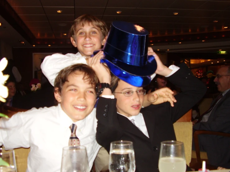 a boy with his arms on the back of another boy holding a blue hat