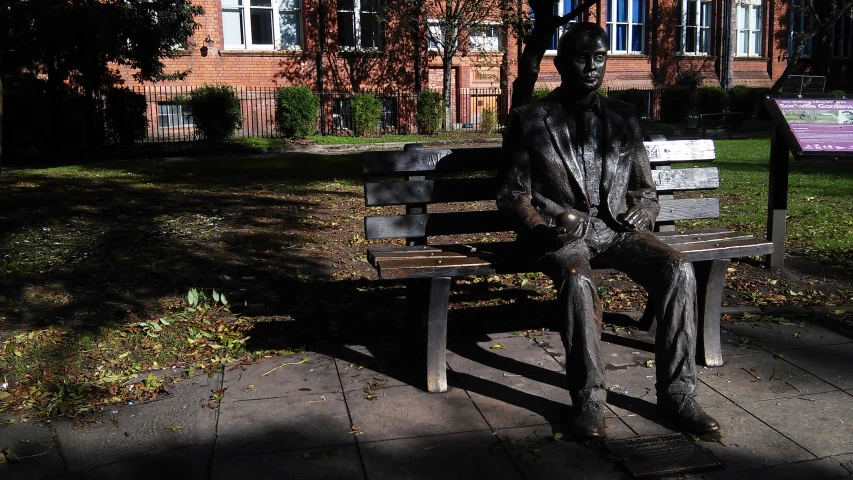 the statue is sitting on the bench outside