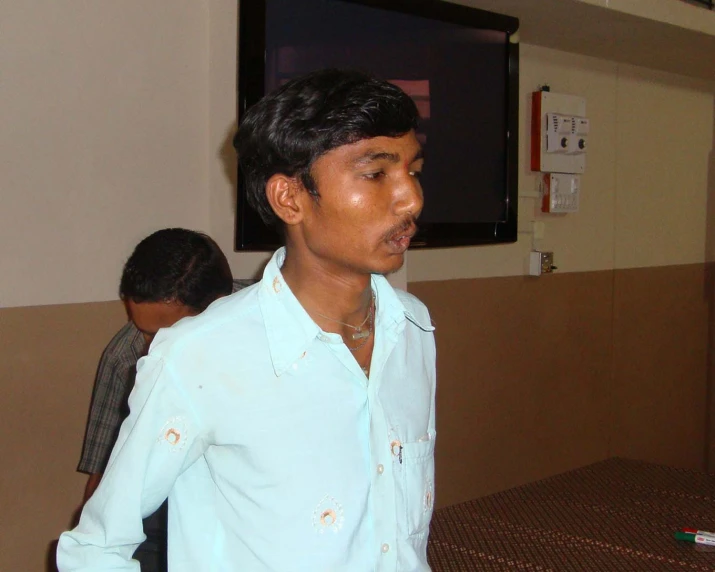 a young man wearing a blue shirt looking at soing