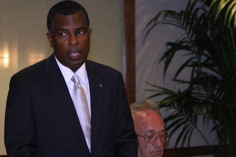 a man in a black suit and tie stands next to an older gentleman