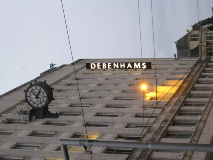 an old clock is displayed above the sign for debenhams