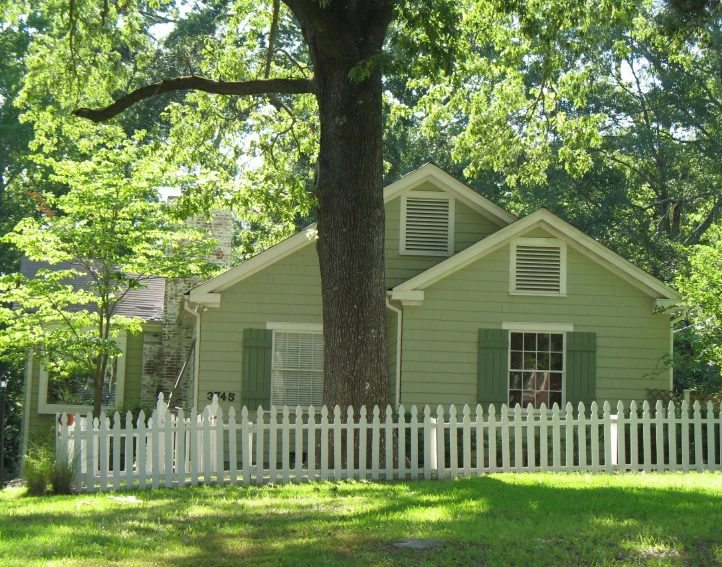 a white fence and green door stands in front of a small home