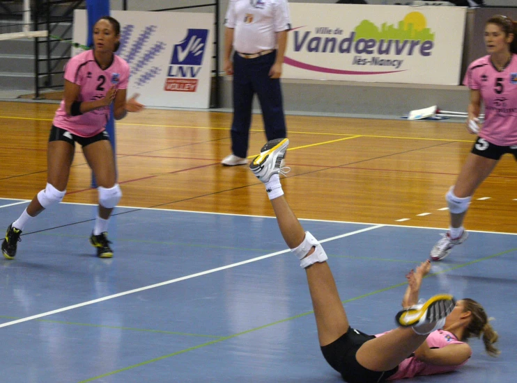 two women in pink uniforms playing a game of volleyball