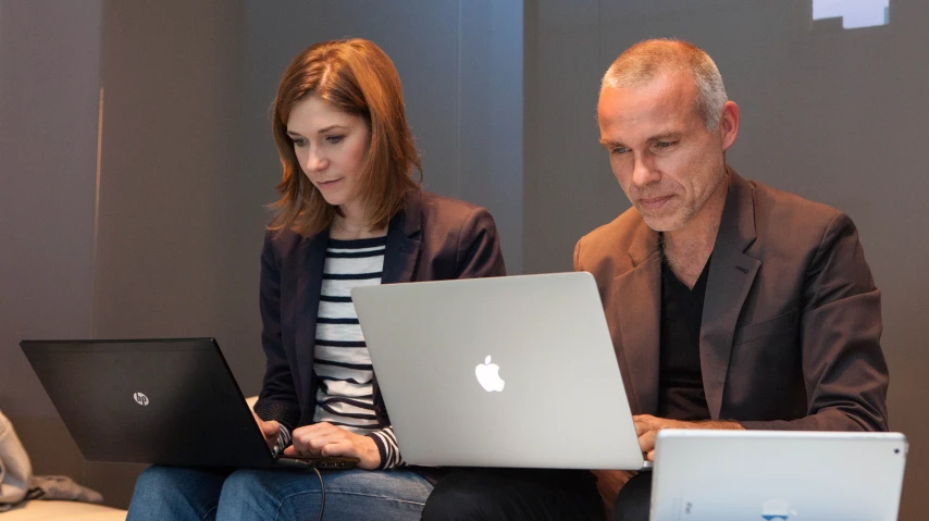 a woman and man on laptops looking at them