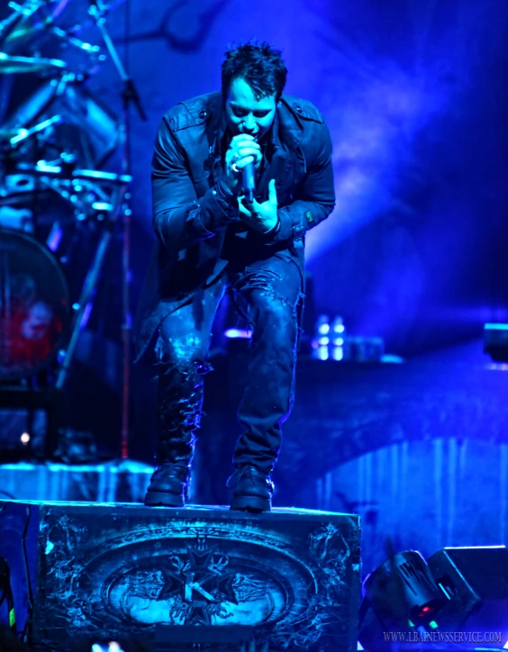 a man in a black jacket and jeans performing on stage
