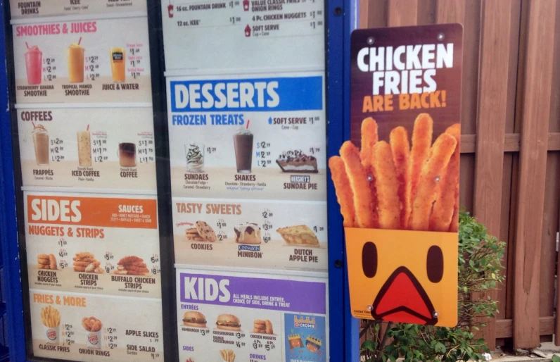 several signs are posted on a wall and show a menu for chicken fries