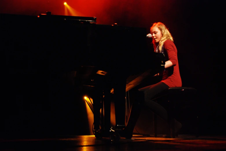 the woman in red shirt is playing piano