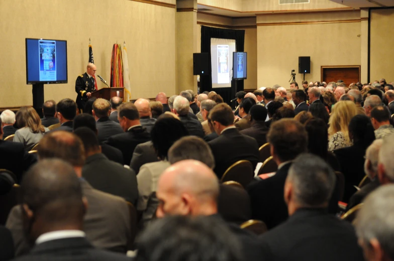 the audience watches as a speaker gives a speech