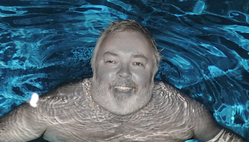 a man swims in a body of water with his mouth open