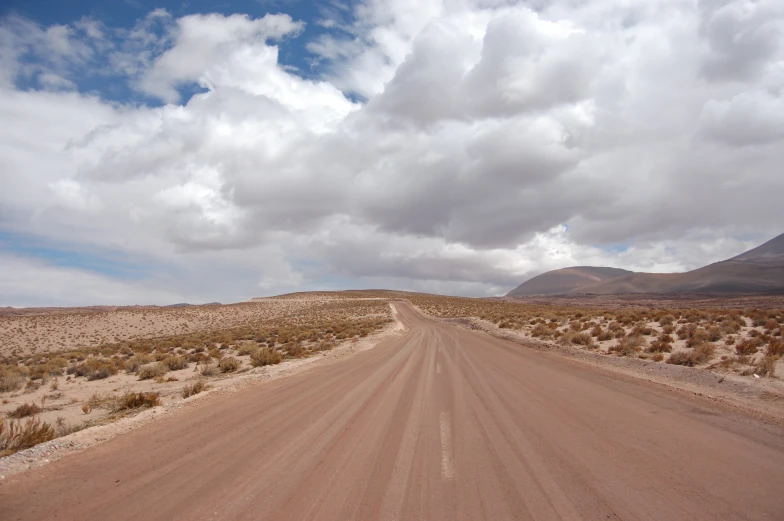 a red road is going down a desert plain