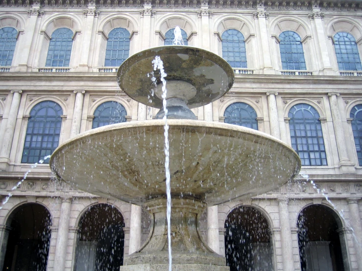 a fountain with water shooting out the top in front of a building