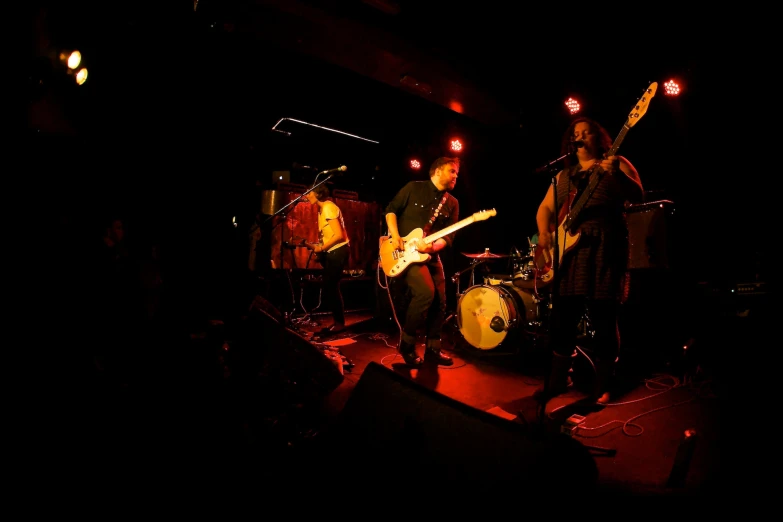 four people playing music on stage at night
