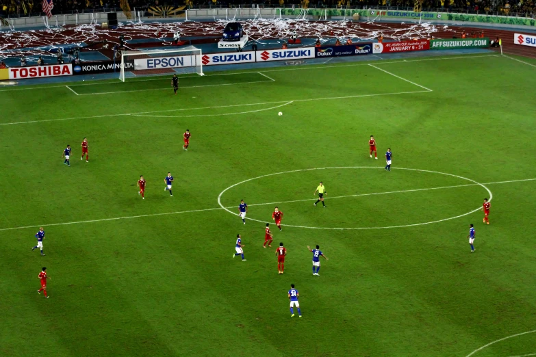 the teams in red are on the grass playing soccer