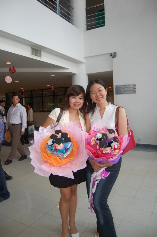 two young women holding up paper flower bouquets