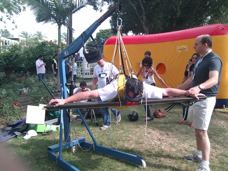 the man on a metal hand swing is being filmed by three people