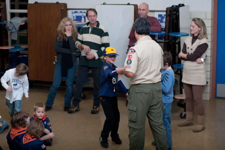 several adults and children are standing near a police officer