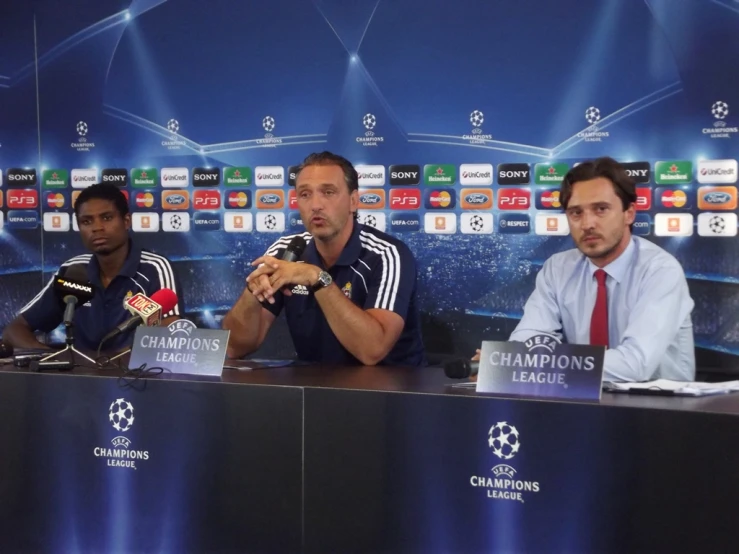 a soccer player sitting in front of microphones