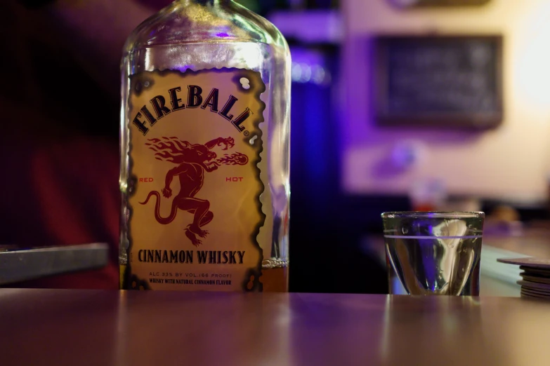 an empty liquor bottle sitting on a counter with a s glass in front