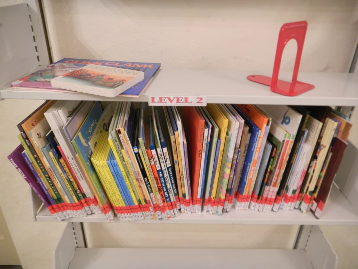 a bookcase with several books on it and a red shelf