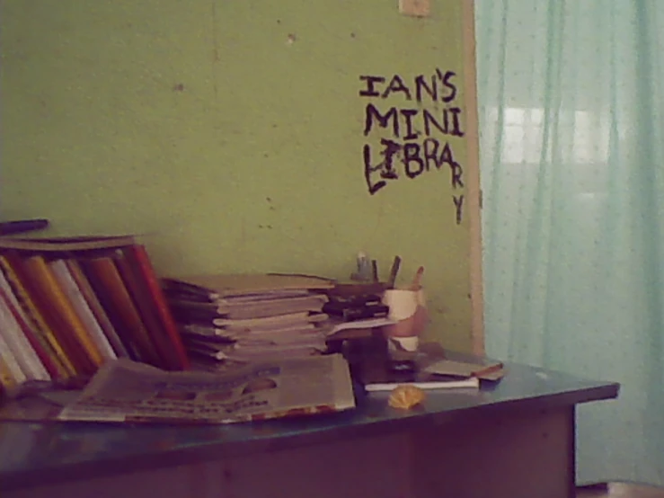 books are sitting on a desk in front of curtains