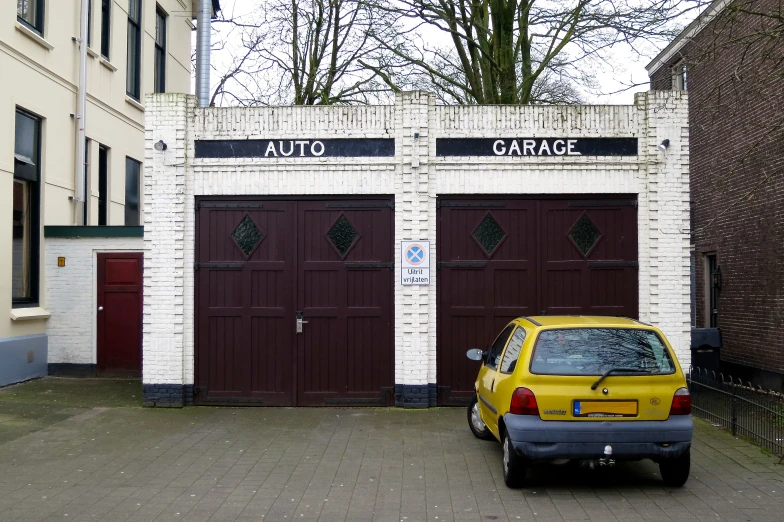 a yellow car parked in front of two brick garages