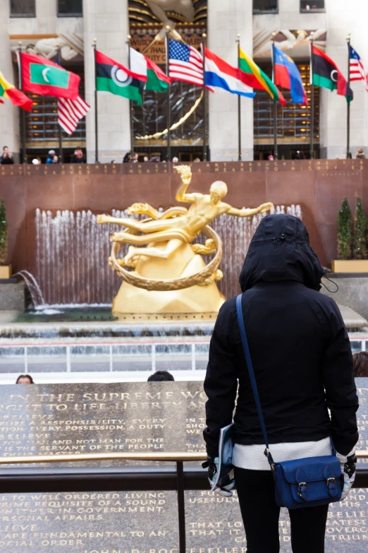 a woman in a black jacket standing at a fountain