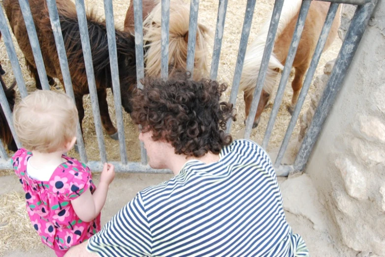 a woman holding a child next to horses