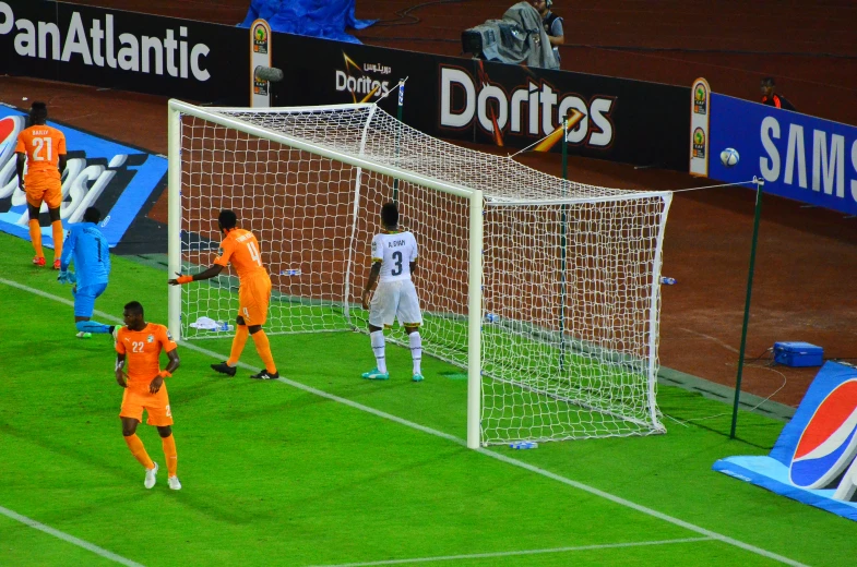 three teams playing soccer during a match with the goalie facing the goal