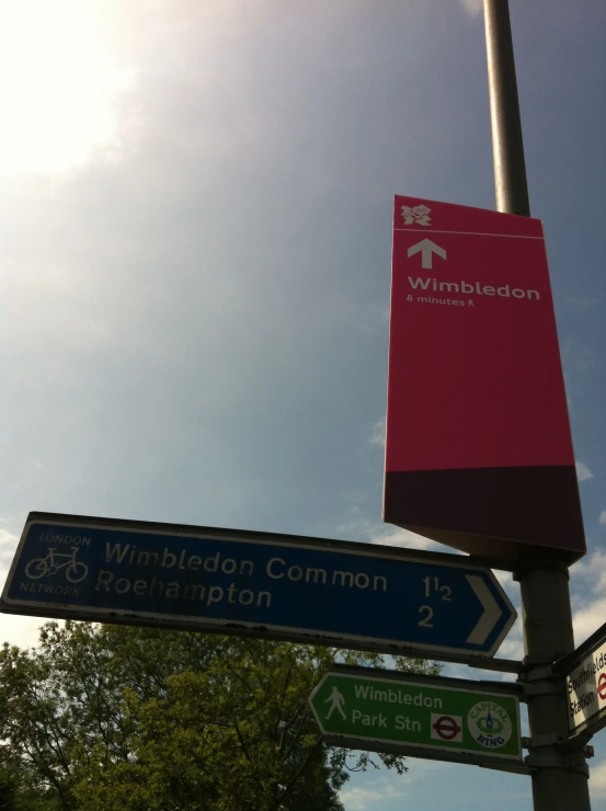 a pink street sign next to a red sign