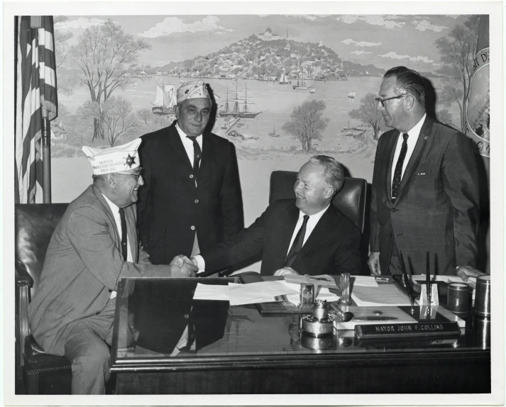 an old black and white po shows five men shaking hands