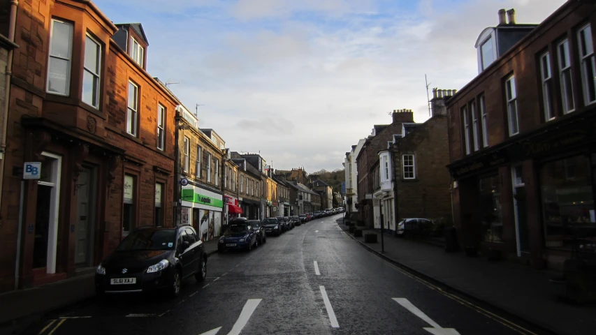 a city street lined with parked cars next to tall buildings