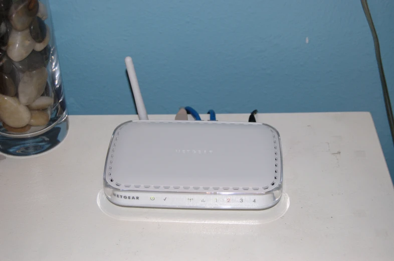 a close up of a wi - fi device sitting on a table near a glass of water