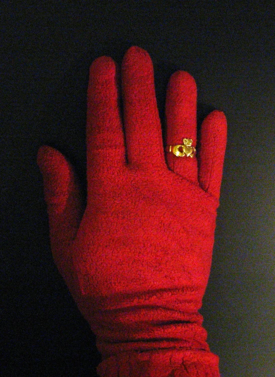 there is a gold diamond ring on top of red glove