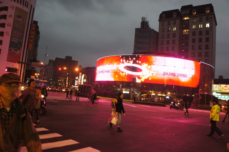 people walking across the street at night, in the city