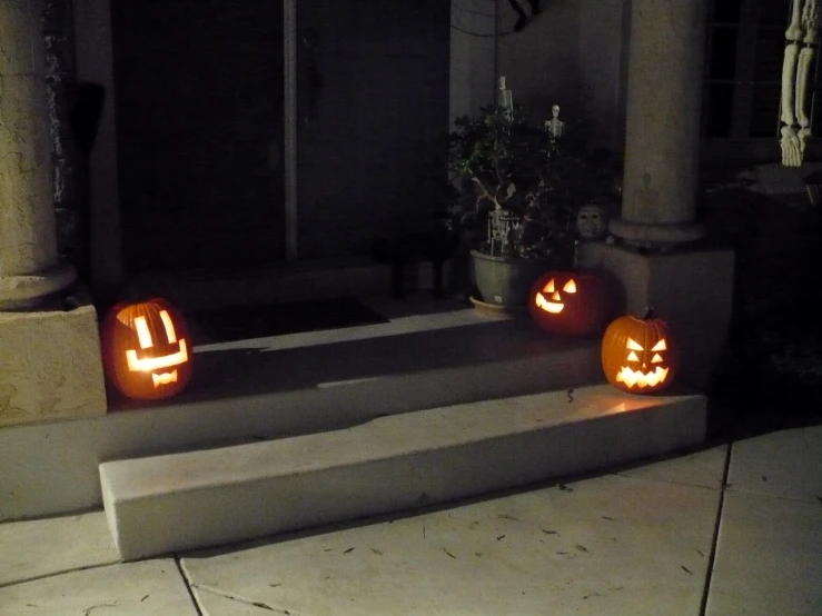 two jack o lanterns sitting on the steps outside of a house