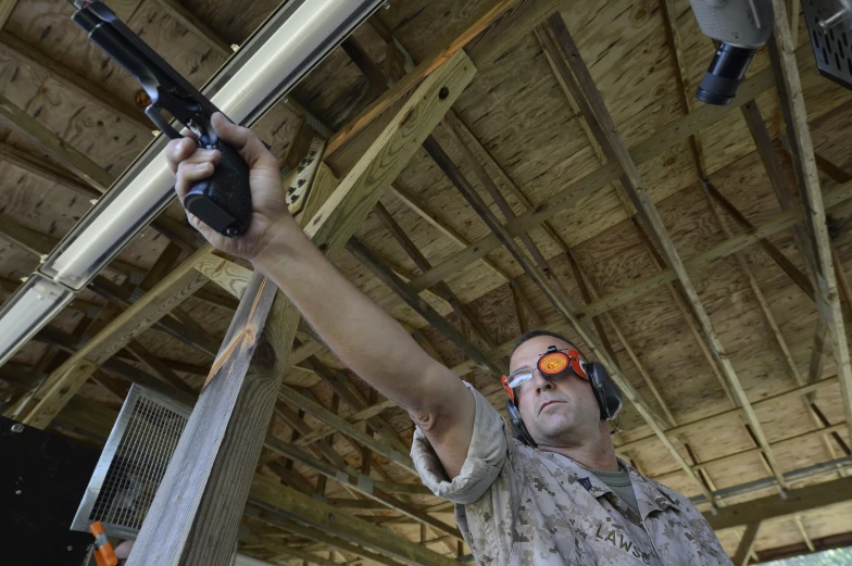 a man with a hat and sunglasses holding up an electronic rifle