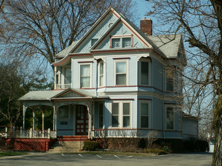 a pretty blue house with two stories next to trees