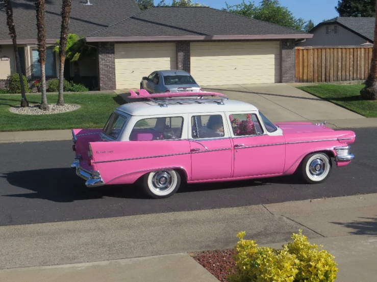a pink station wagon with a white top parked on a residential street