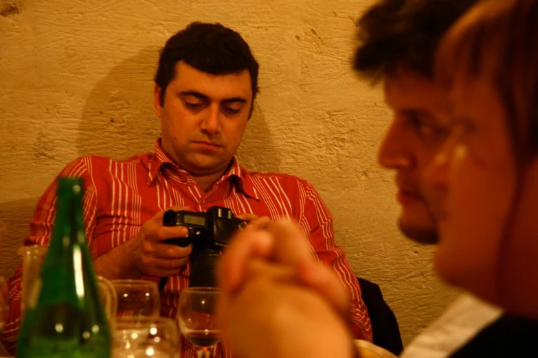 a man looking at his phone while sitting next to another woman