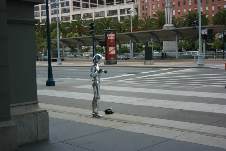 a metal man statue in the middle of the road