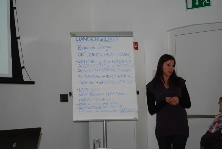 a woman giving a seminar in front of a board