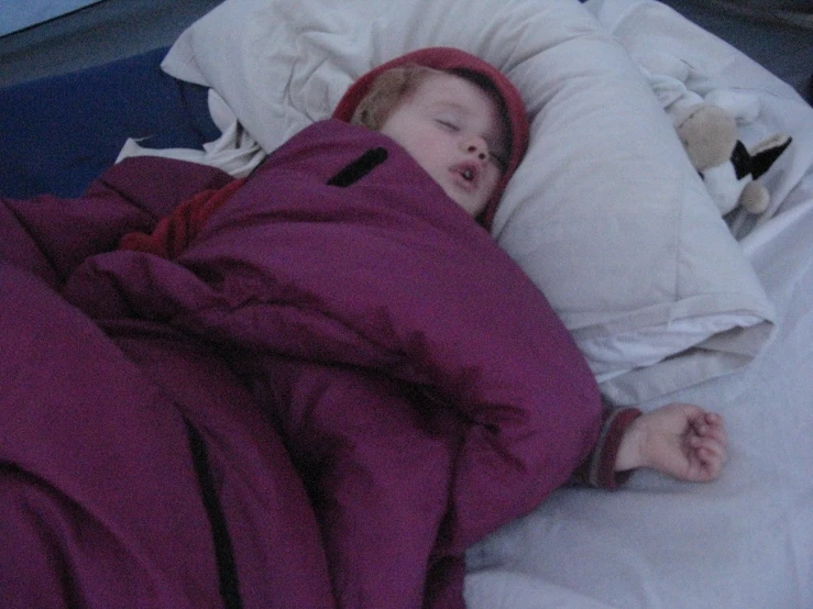 an infant in bed covered by blankets and pillows