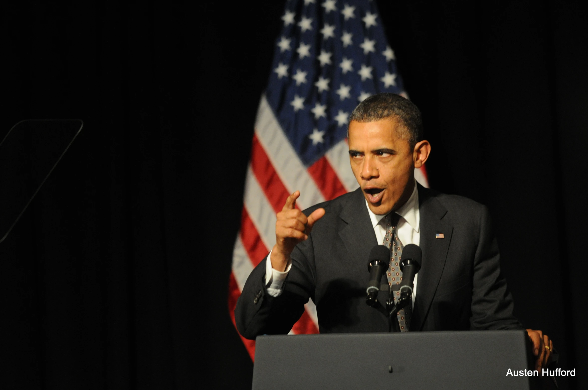 a man speaking at a podium in front of american flags