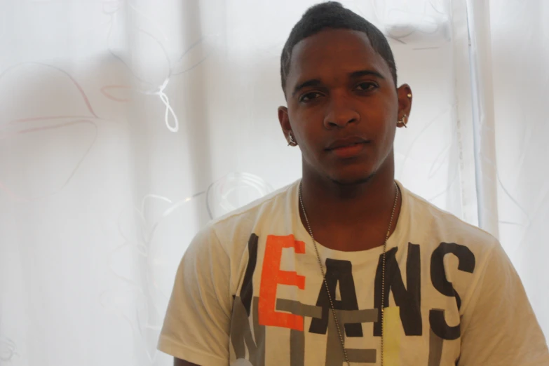 a young man posing for a po in front of white curtains