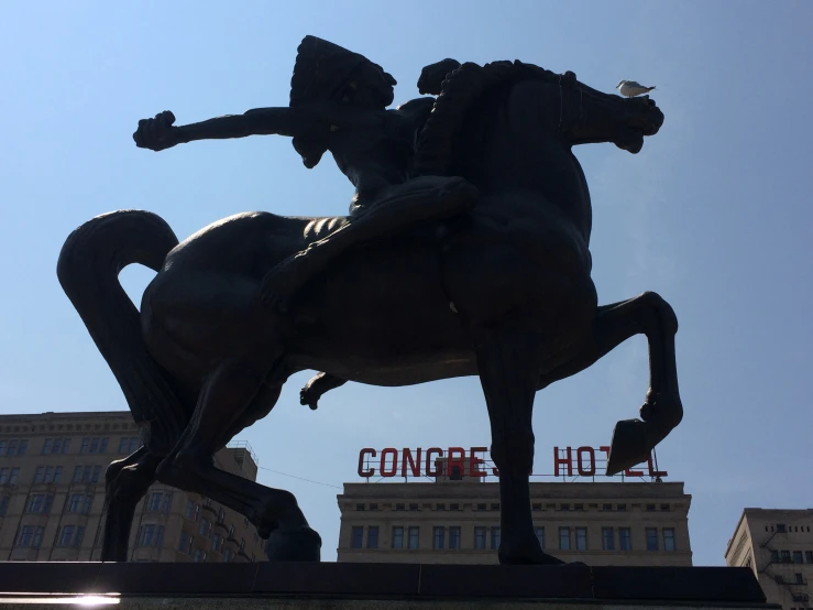 statue of a jockey on a horse in front of a large el