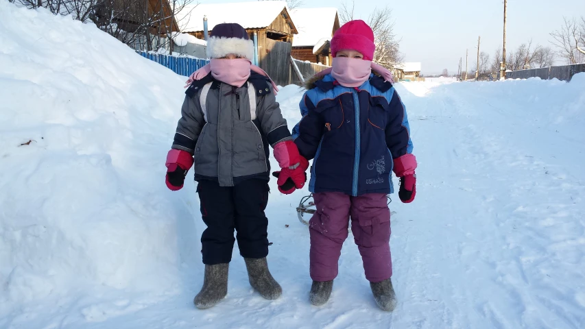 two young children playing in the snow outside