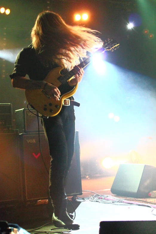 a woman in tight jeans holding a guitar in front of the microphone