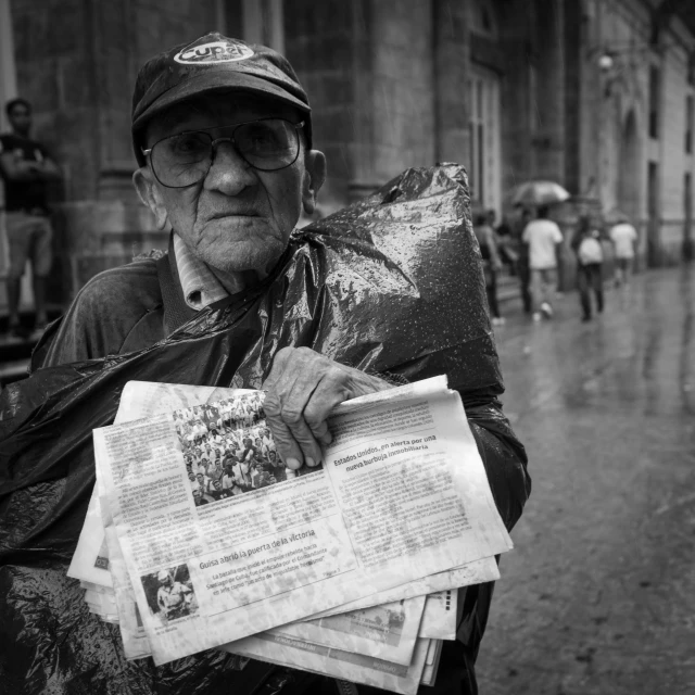 an old man holding a newspaper and a large bag