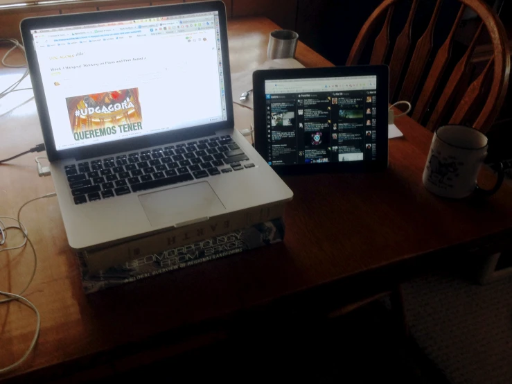 two computers sitting side by side on top of a wooden desk