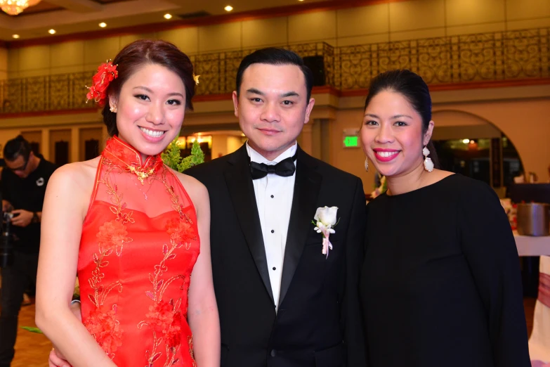 three people standing together in formal attire